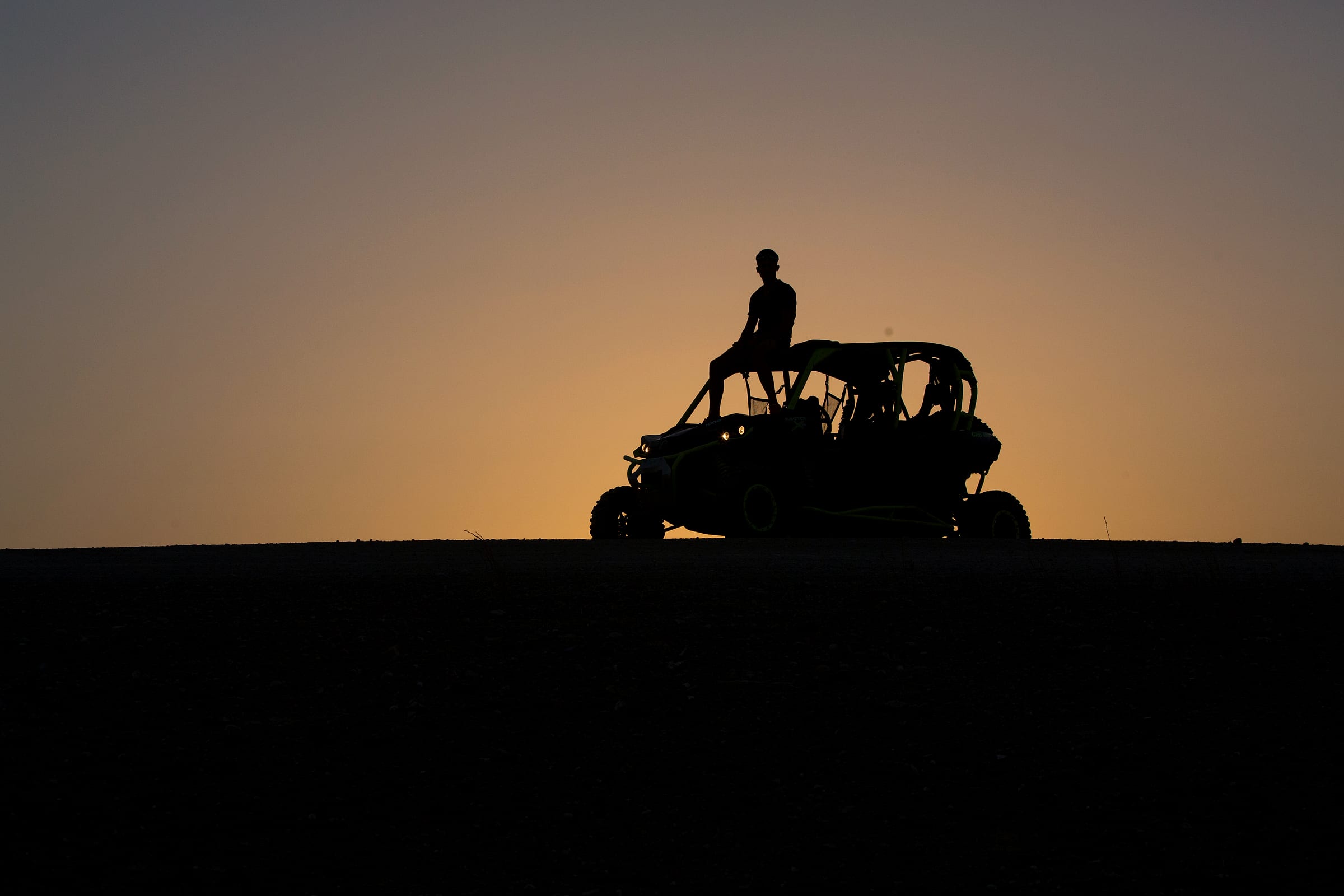 Buggy en silhouette sur une crête d'Agafay au coucher du soleil
