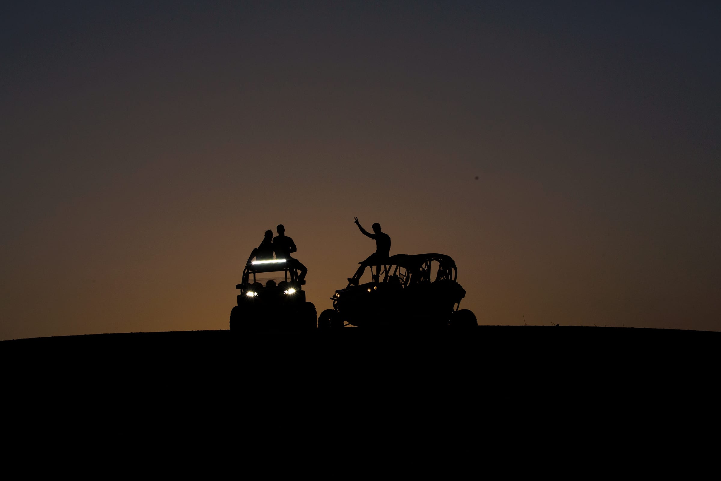 Buggy en silhouette sur une crête d'Agafay au coucher du soleil