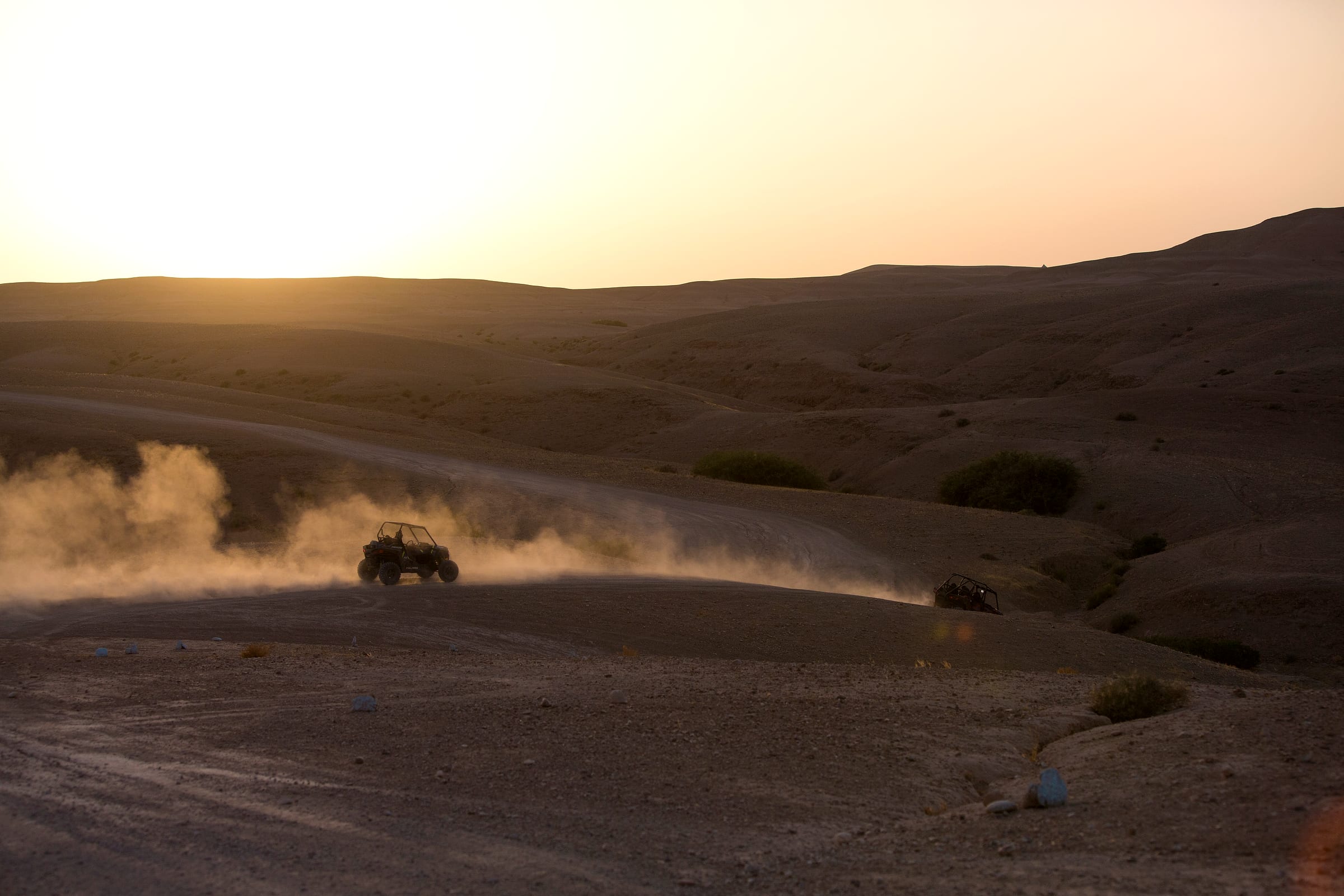 Vaste plateau rocheux d'Agafay, buggy minuscule au loin sur la piste