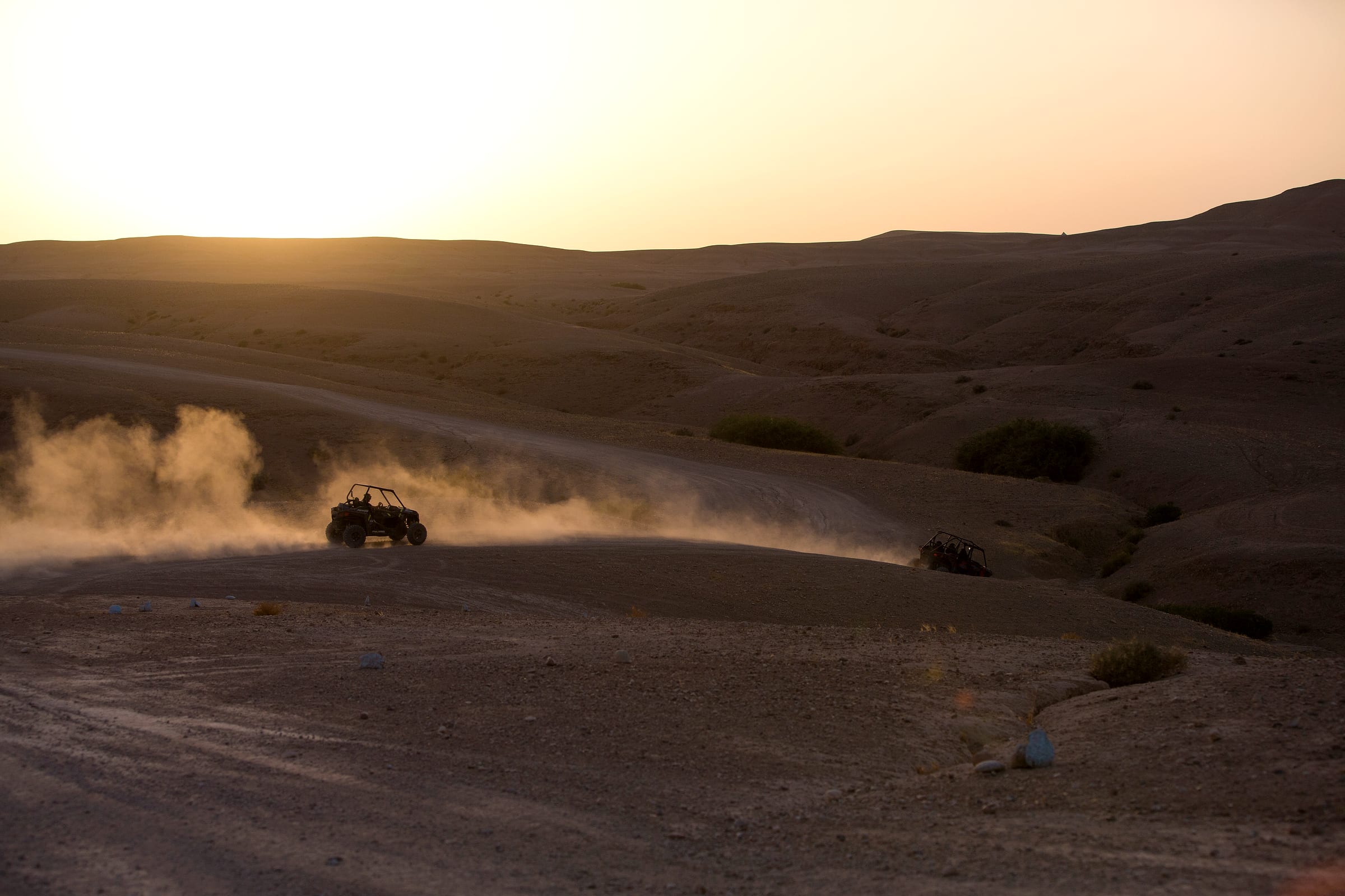Vaste plateau rocheux d'Agafay, buggy minuscule au loin sur la piste